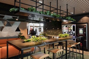 A modern bar area with a long counter, bar stools, and a seating area with orange sofas. - Citybox Bergen Danmarksplass (Bergen)