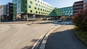 A modern multi-story hotel with a green facade, a covered entrance, and a pedestrian crossing. - Citybox Bergen Danmarksplass (Bergen)