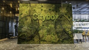 A modern interior with a moss-textured wall and two black wire chairs. - Citybox Bergen Danmarksplass (Bergen)