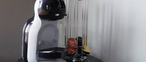 Una macchina da caffè Nespresso su un tavolino con una caraffa in vetro e un portacaffè in metallo.