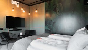 A modern hotel room with a large bed, a flat-screen TV, a desk with a chair, and a mural on the wall. - Citybox Bergen Danmarksplass (Bergen)