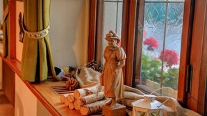 A rustic interior with a wooden bench, logs, and a statue. - Lenzkircher Hof (Lenzkirch)