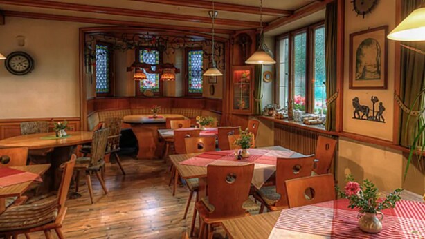 A cozy restaurant with wooden tables and chairs, stained glass windows, and a clock on the wall. - Lenzkircher Hof (Lenzkirch)