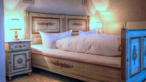 A bedroom with a wooden bed, white bedding, and a nightstand with a lamp. - Lenzkircher Hof (Lenzkirch)