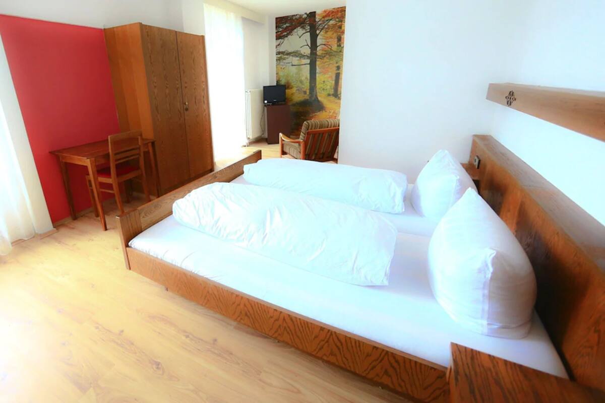 A bedroom with a wooden bed, a desk, and a chair.