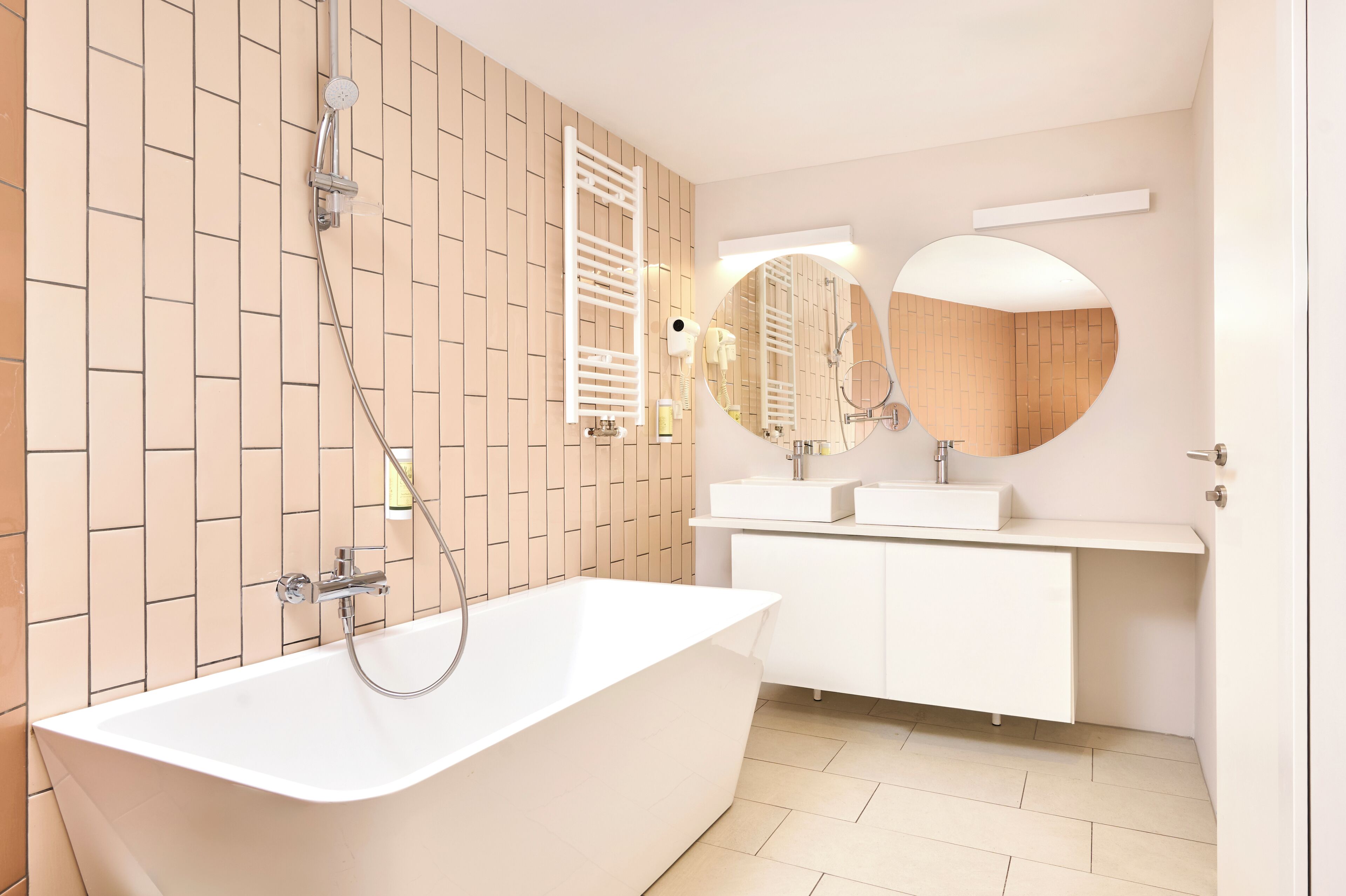A modern bathroom with a freestanding bathtub, a vanity with two sinks, and a large mirror.