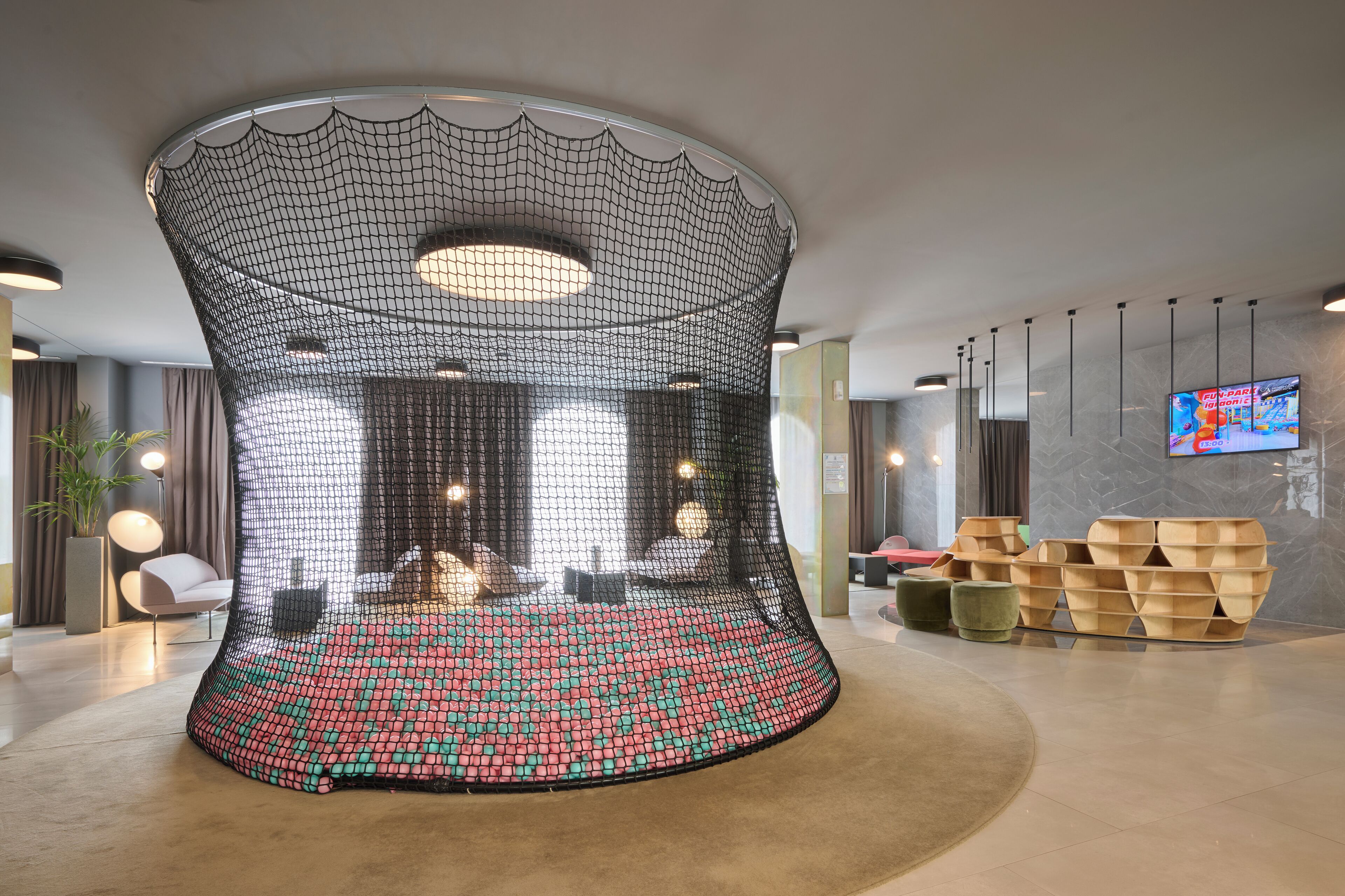 A modern lobby with a unique curved seating area, a flat-screen TV, and contemporary furniture.