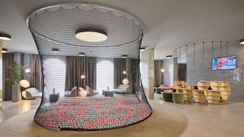 Un hall d’entrée moderne doté d’un espace salon aux lignes courbes originales, d’un téléviseur à écran plat et de mobilier contemporain.