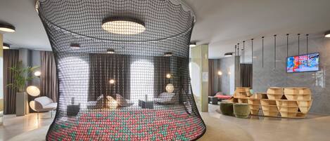 A modern lobby with a unique curved seating area, a flat-screen TV, and contemporary furniture.