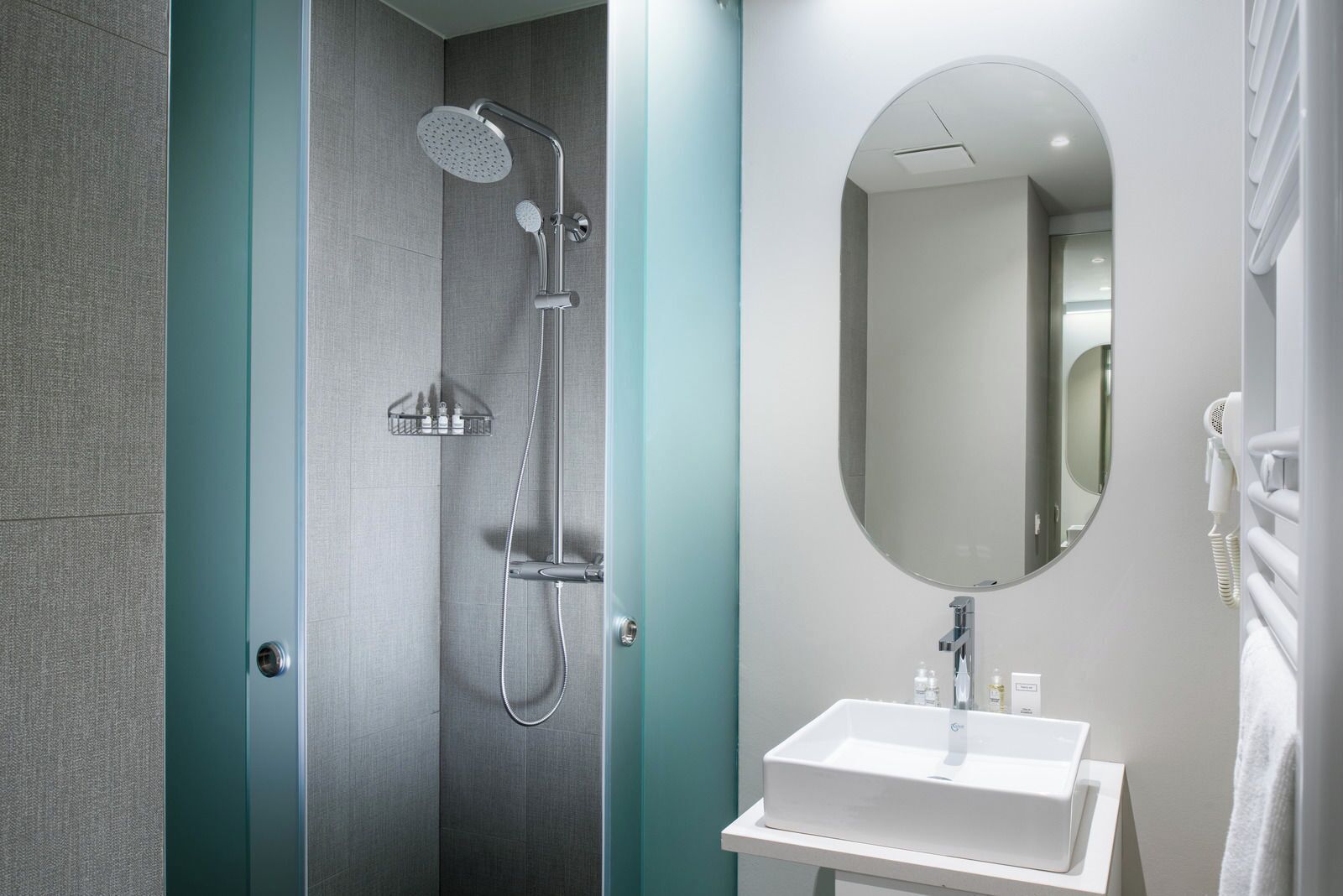 Un baño moderno con ducha, lavamanos y espejo.