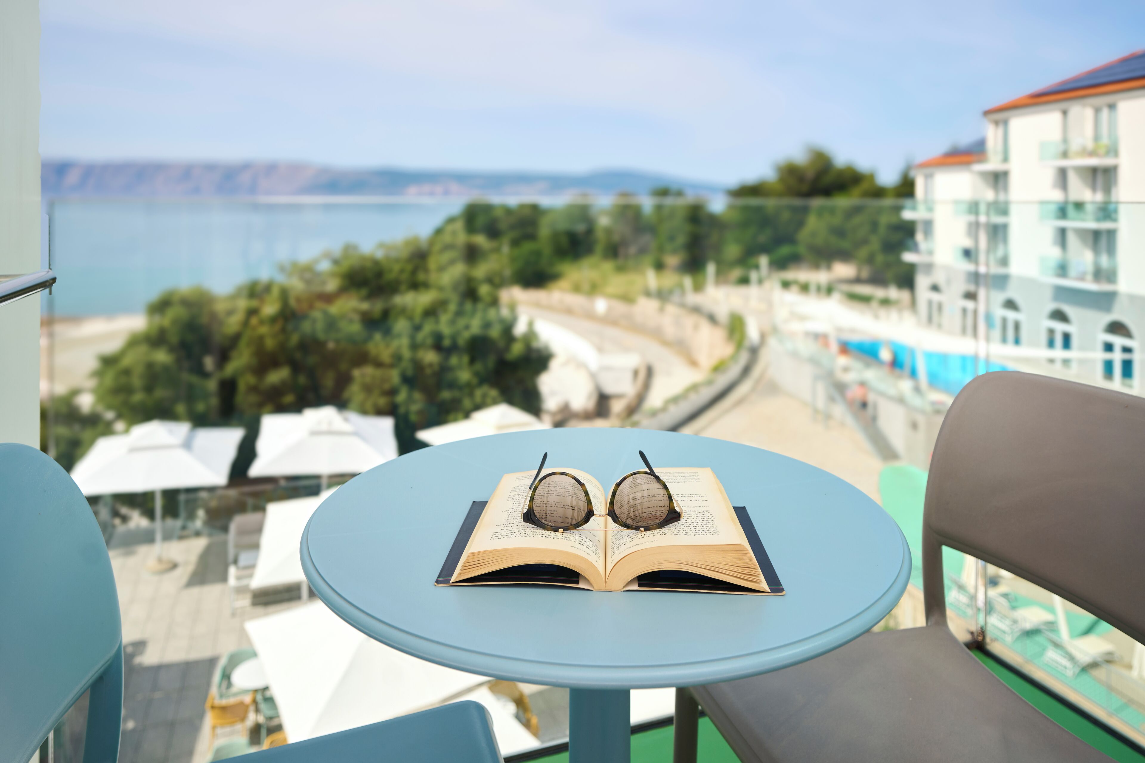A balcony with a table, a book, and a pair of glasses.