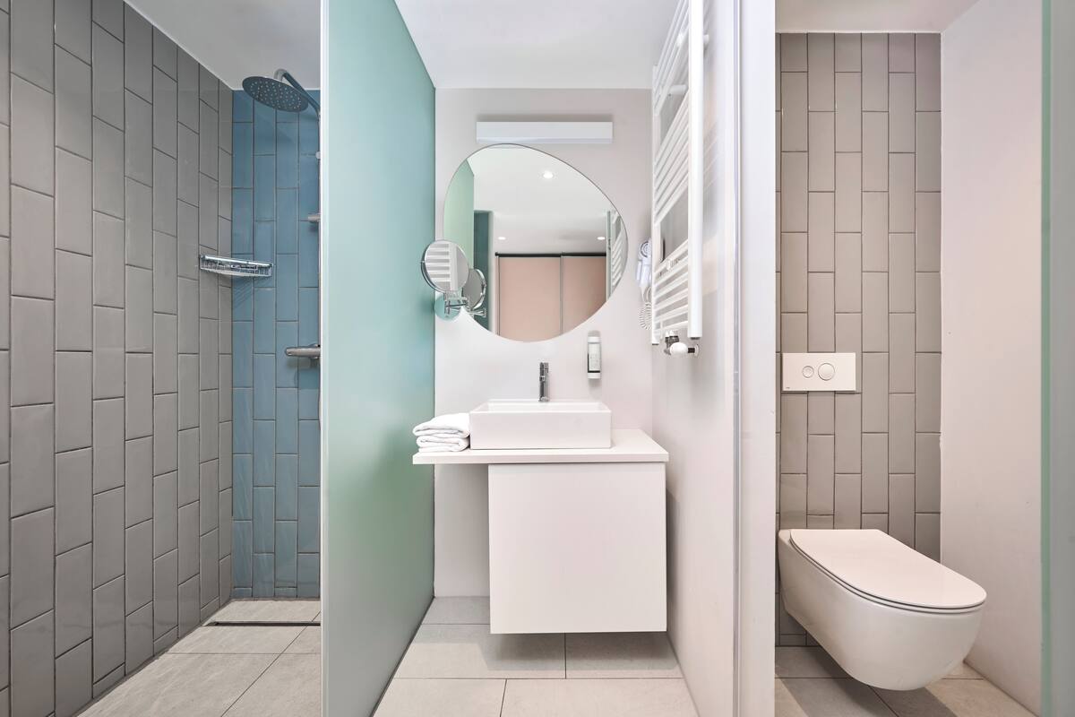 A modern bathroom with a shower, sink, and toilet.