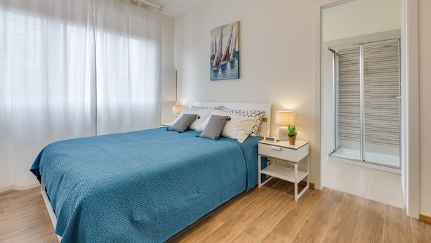 A bedroom with a bed, nightstands, a painting, a window with blinds, and a curtain. - Rooms Vidar Train station (Mestre)