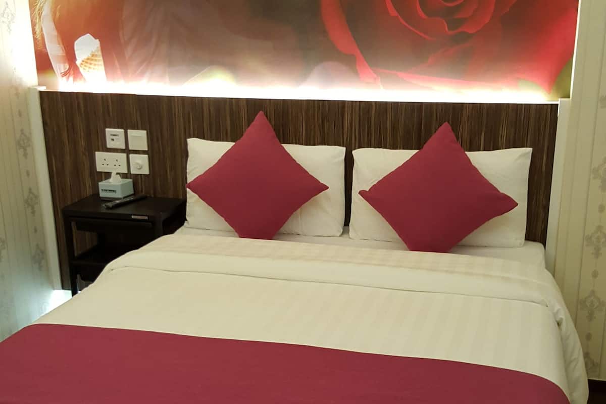 Ein Bett mit einer weiß-roten Tagesdecke, zwei roten Kissen und einem großen gerahmten Bild einer roten Rose am Kopfteil.