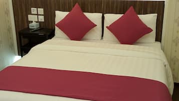 A bed with a white and red bedspread, two red pillows, and a large framed picture of a red rose on the headboard.