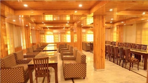 A spacious dining area with wooden walls and ceiling, featuring multiple dining tables and chairs.