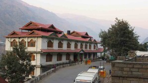 A multi-story building with a red roof and white walls, located in a mountainous area.