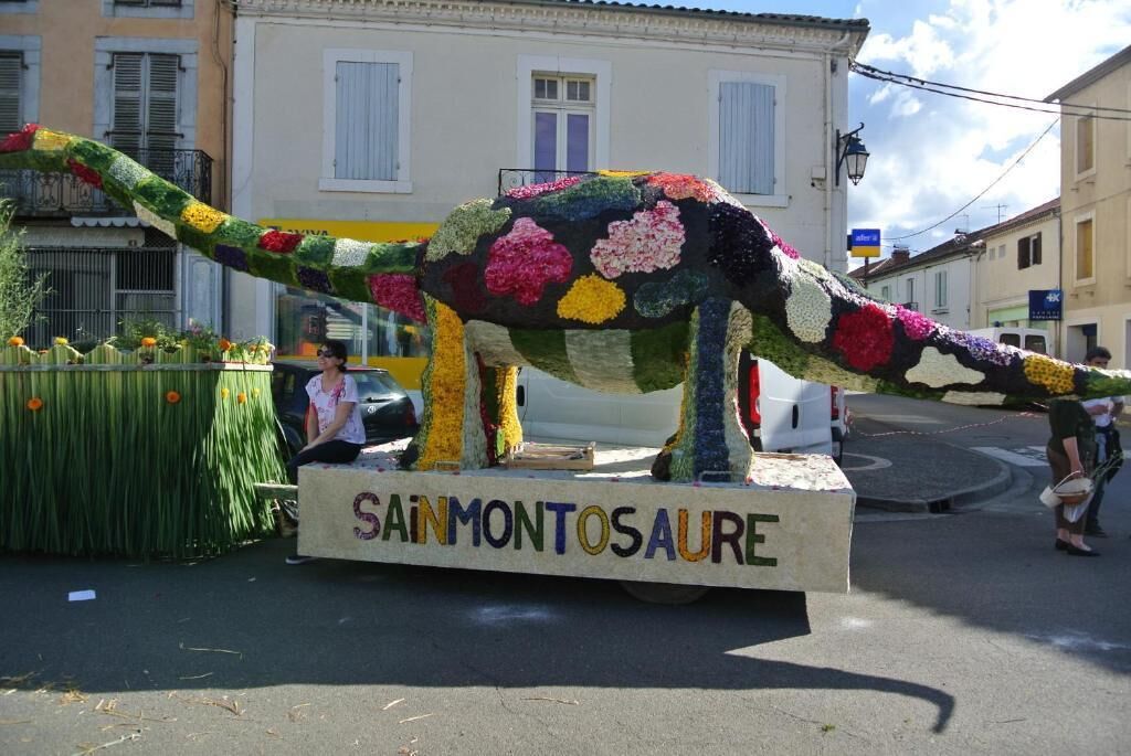 A dinosaur sculpture made of flowers on a platform with "SAINT-MONTOSAURE" written on it.