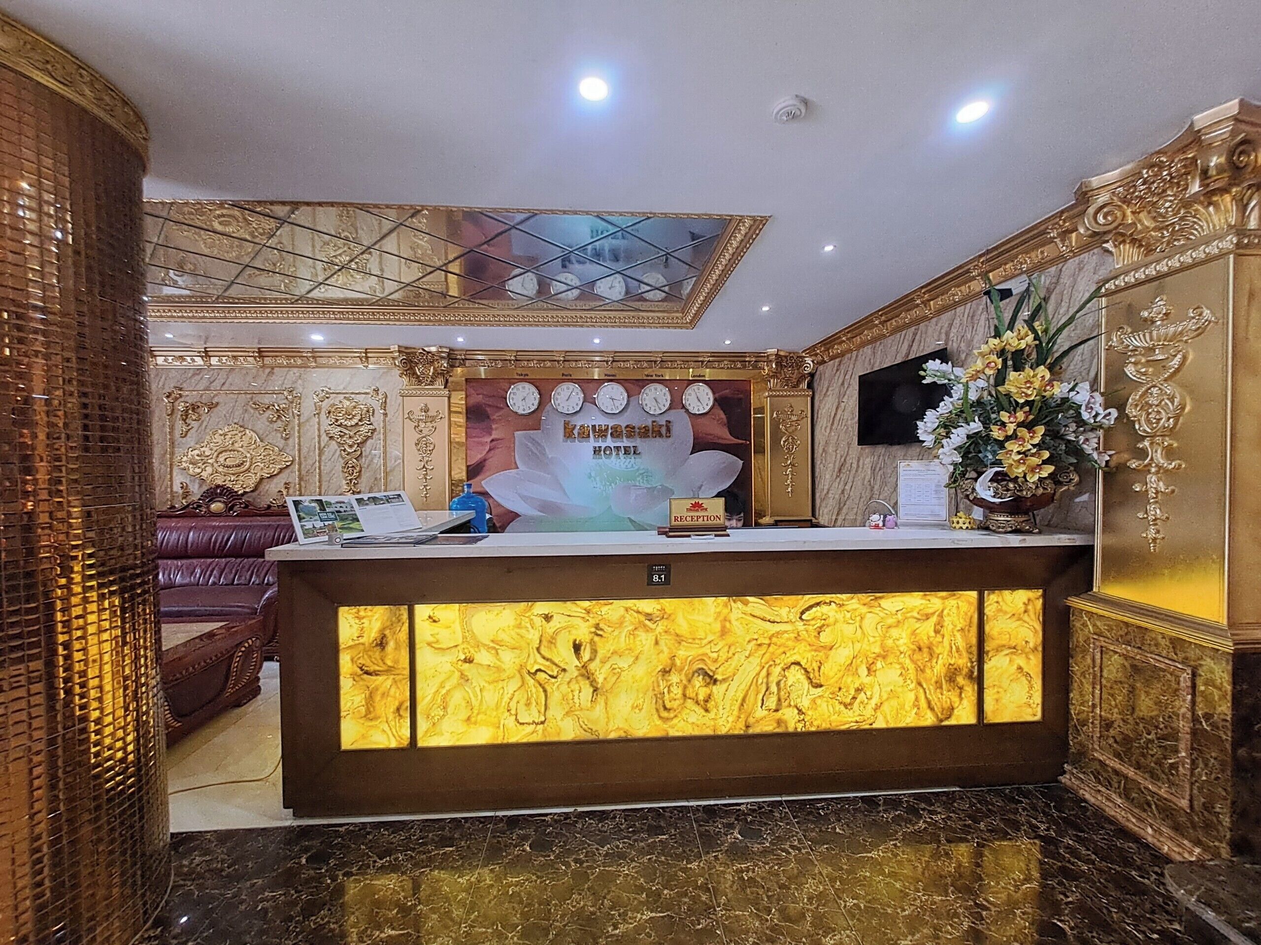 A hotel reception area with a marble counter, a reception desk, a clock, and a flower arrangement.