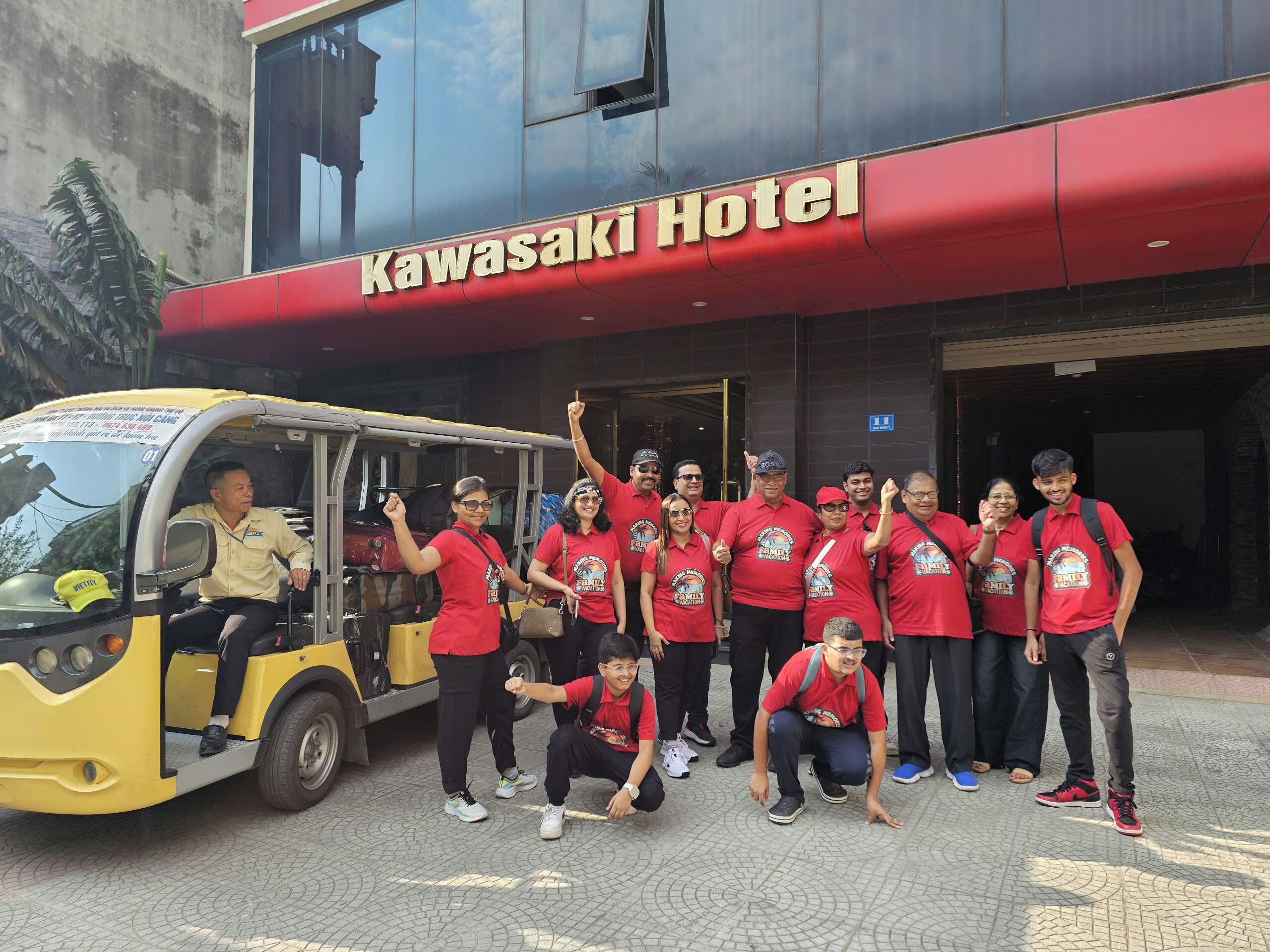A group of people in red shirts posing in front of the Kawasaki Hotel.