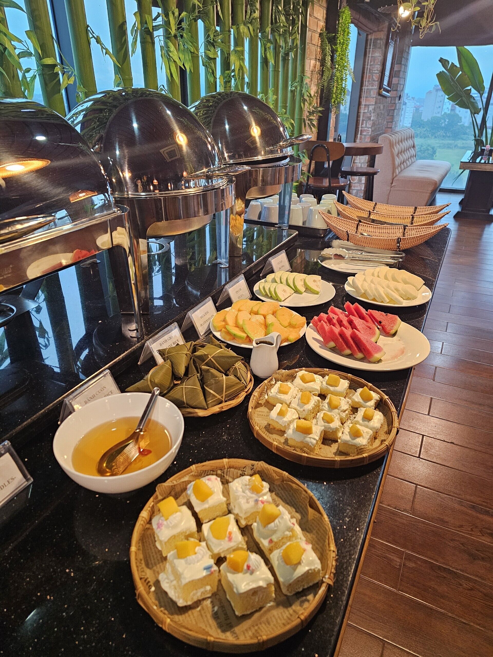 Een buffet met diverse gerechten, waaronder fruit, desserts en een soepkom.