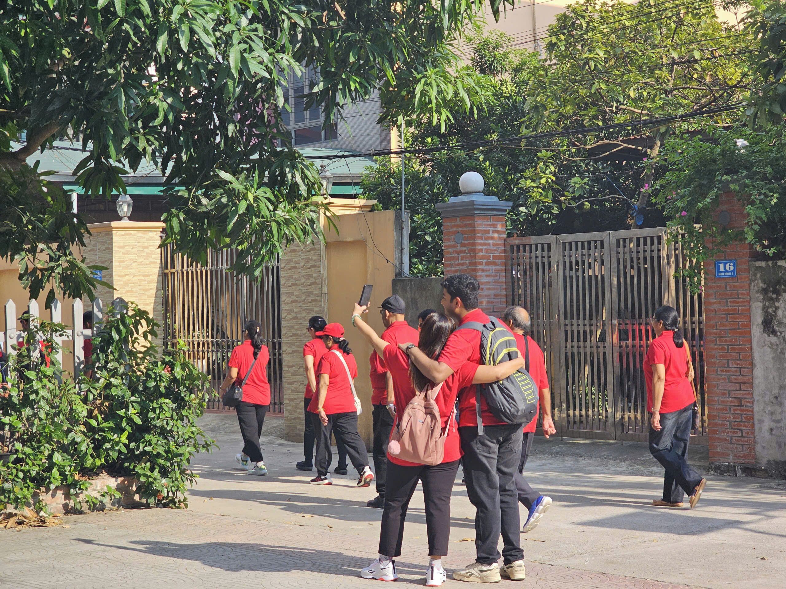 Un grupo de personas con uniformes rojos caminando hacia una entrada con reja.