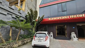 Un coche blanco estacionado frente al Hotel Kawasaki.