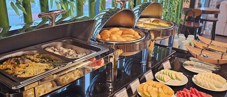 Un bufé con diferentes opciones de comida, como fideos, dumplings y frutas.