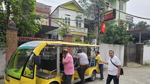 Un tuk-tuk amarillo estacionado frente a un edificio con un cartel que dice 