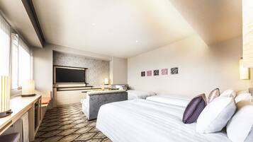 Habitación de hotel con cama, escritorio, televisión y una kitchenette pequeña.