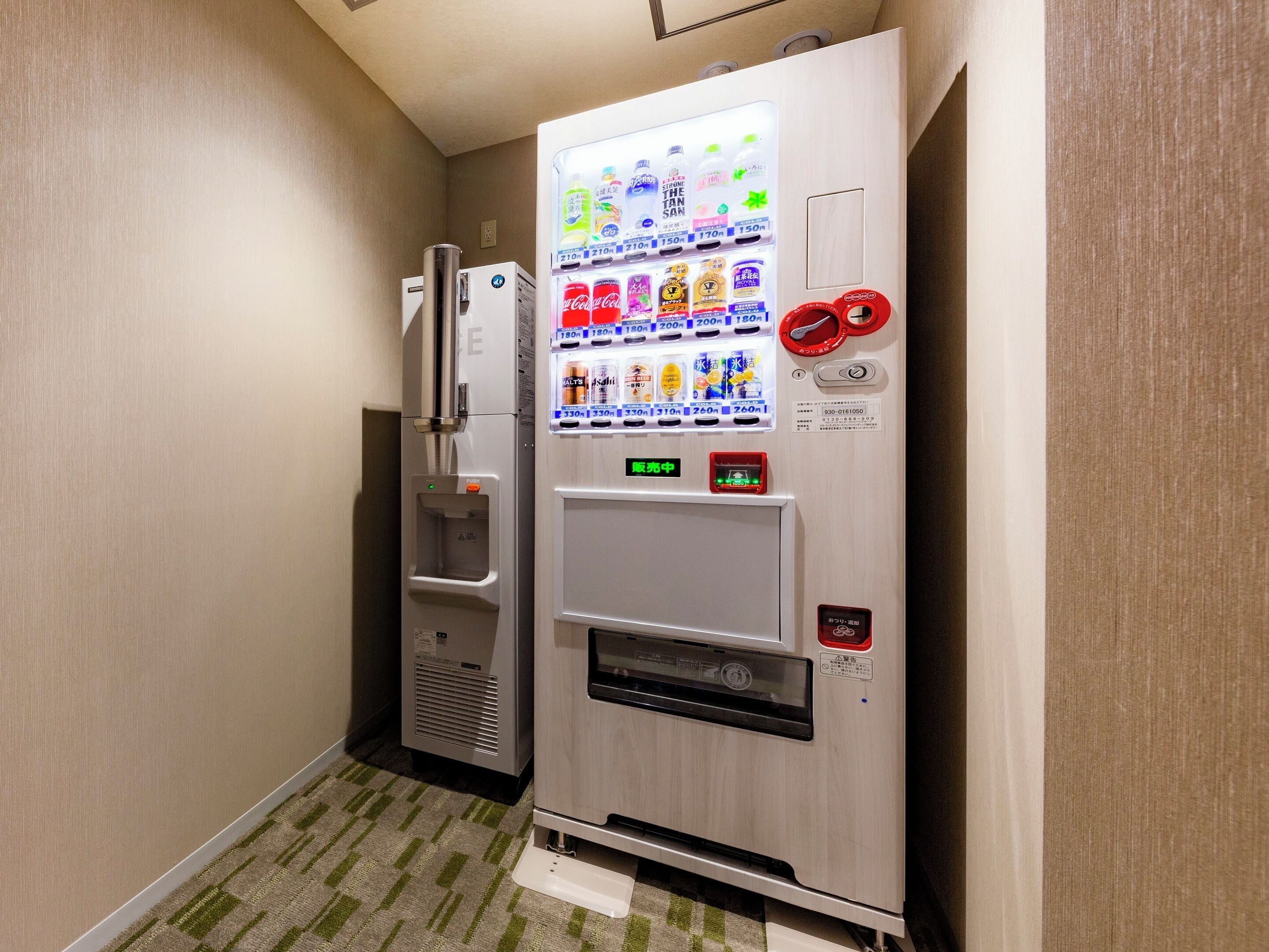 A vending machine with a variety of drinks and a water dispenser in a hallway.