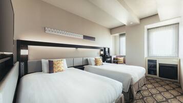 A hotel room with two beds, a desk, a chair, a small table, and a window with curtains.