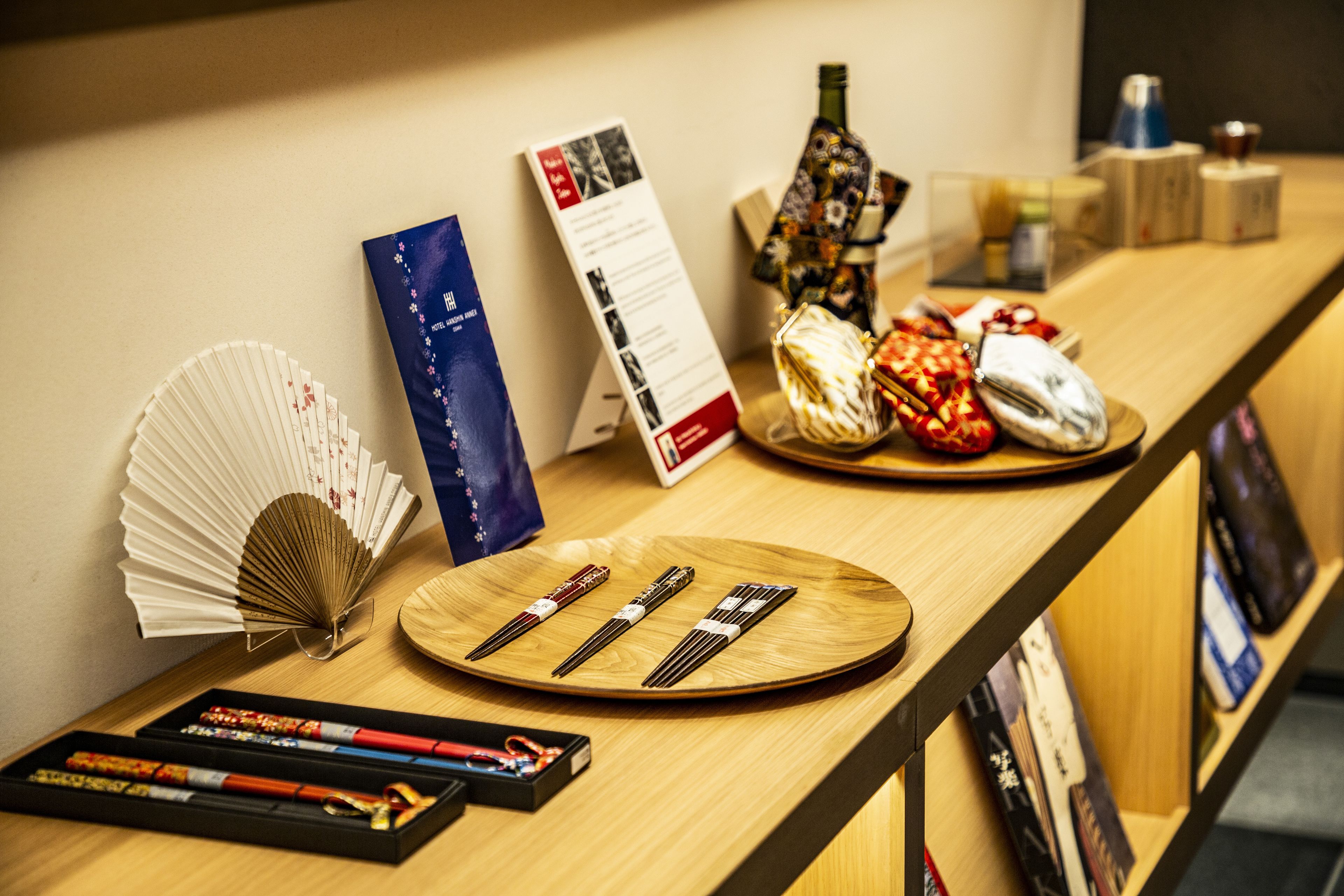 A wooden reception desk with a fan, a menu, and various items including a bottle and a decorative object.