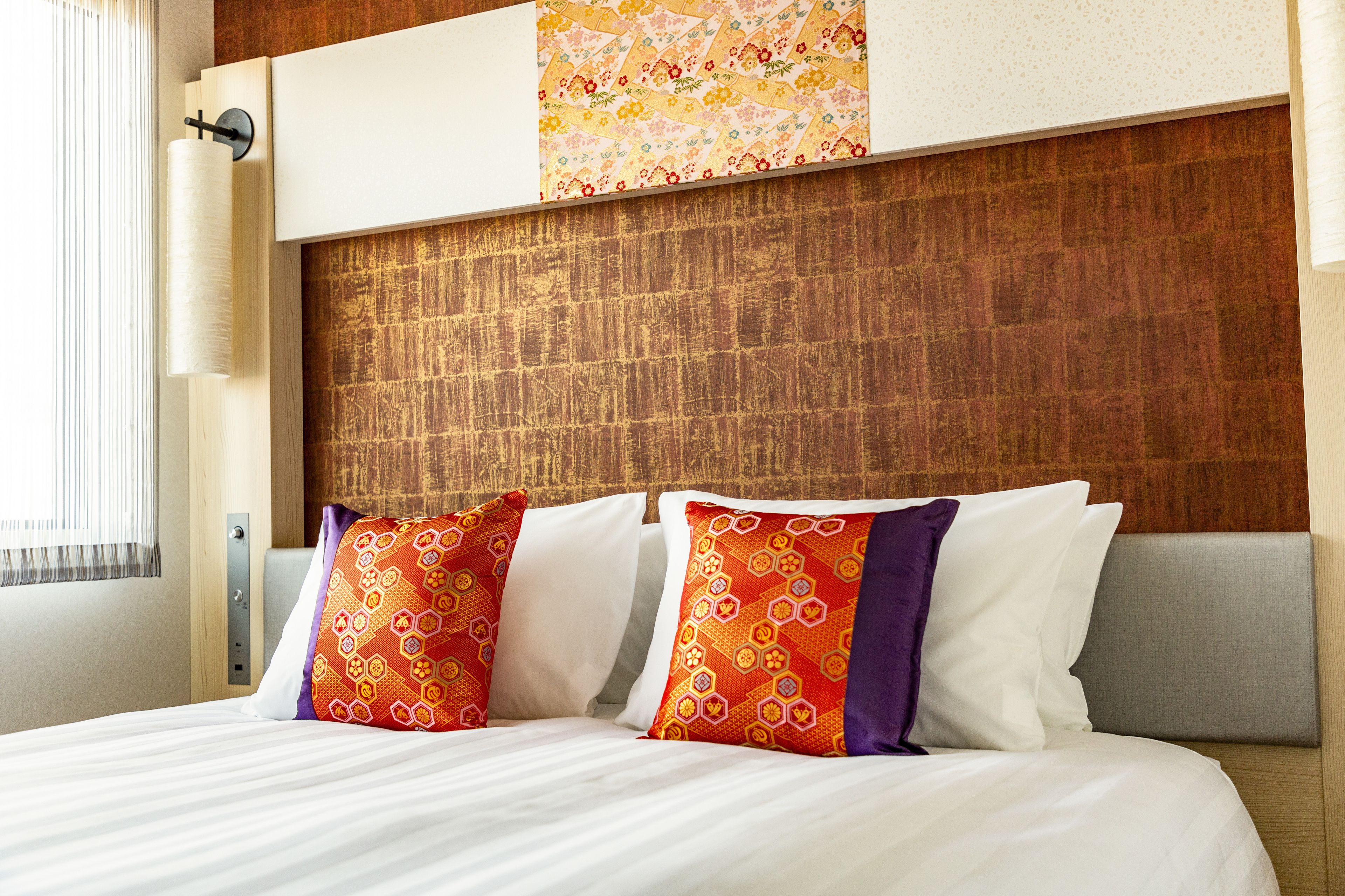 A hotel room with a wooden headboard, a bed with white linens, and decorative pillows.