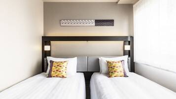 A hotel room with two beds, a headboard with a light fixture, and a decorative wall piece above the beds.