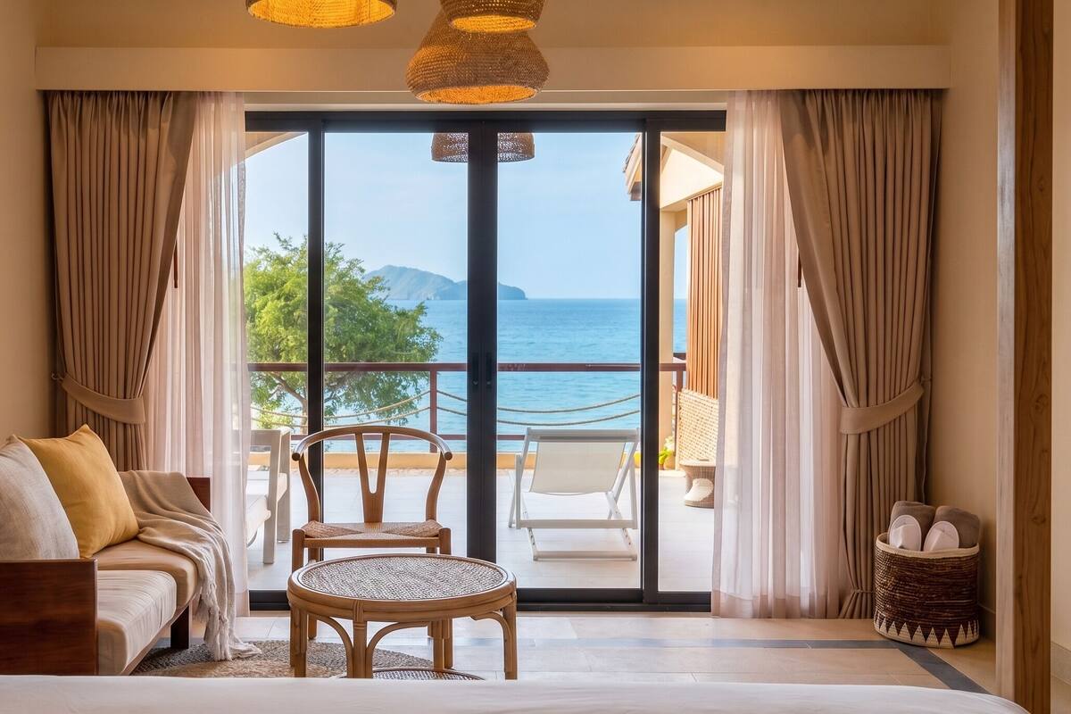 Une chambre à coucher comprenant un lit, une chaise, un canapé et offrant une vue sur la mer grâce à une grande fenêtre.