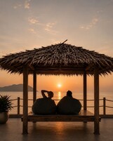 Un pabellón de madera con techo de paja que da vista a un cuerpo de agua al atardecer.