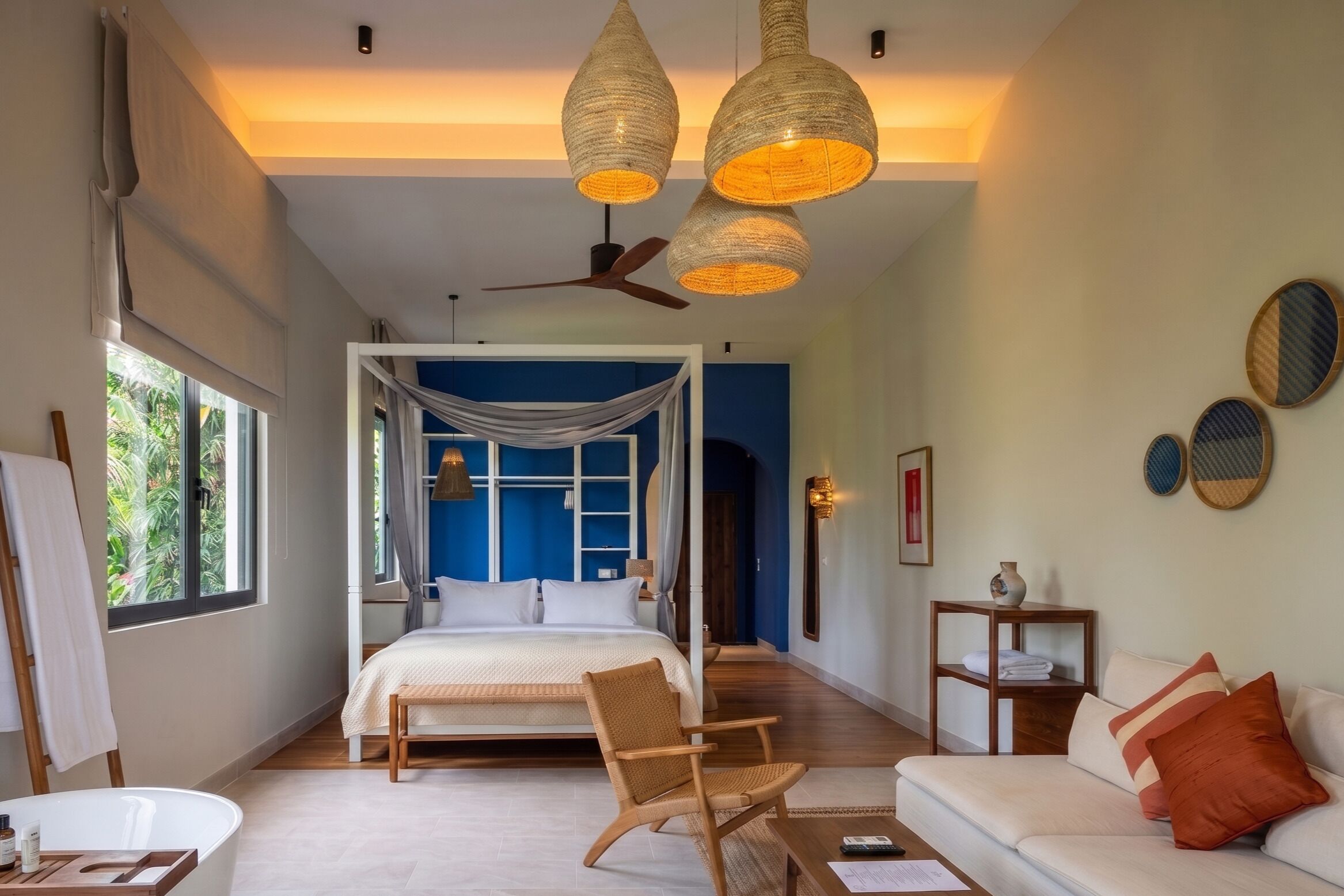 A bedroom with a bed, a chair, a sofa, a small table, and a ceiling fan.