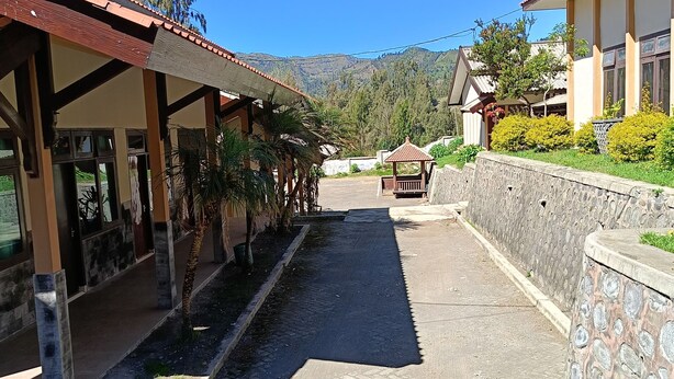 Un sendero que lleva a un edificio con un porche cubierto y un muro de piedra.