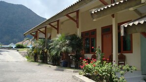 Un edificio con techo de tejas rojas, un patio cubierto y una montaña al fondo.