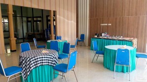 Un salón de conferencias con mesas y sillas, una mesa de buffet y un ventanal grande.