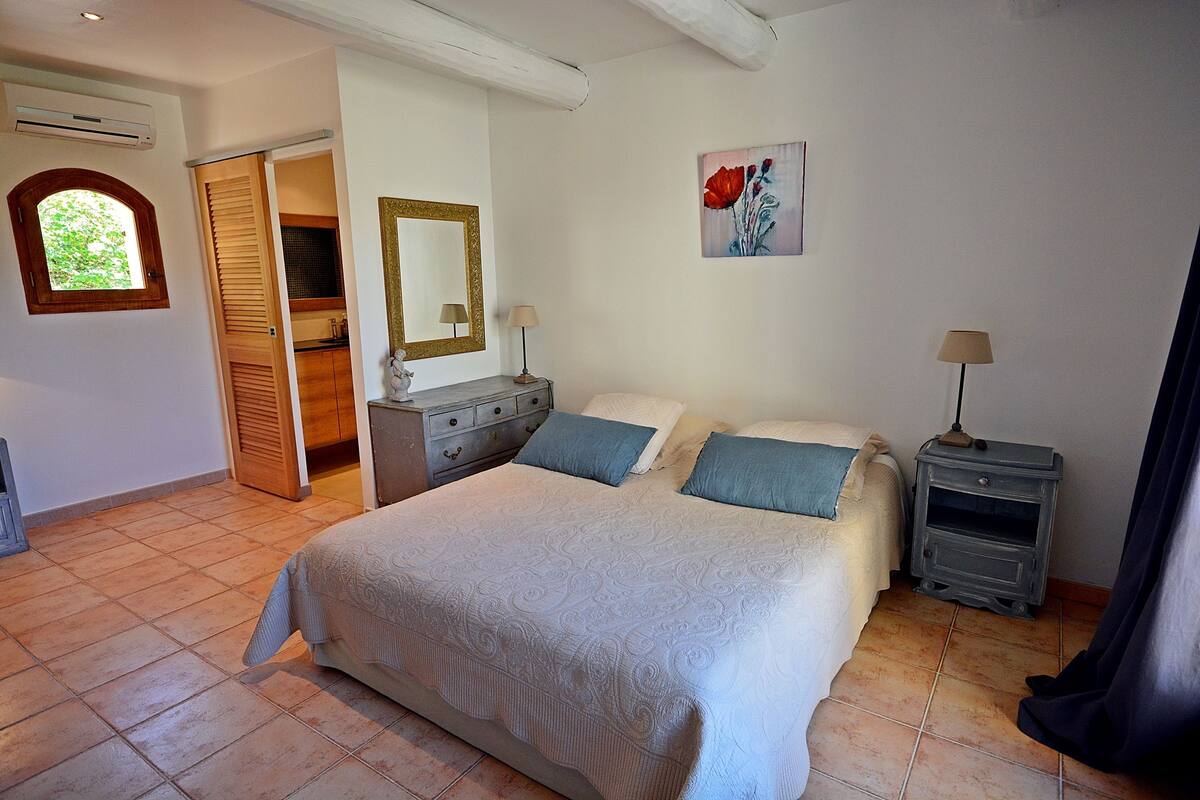 Een slaapkamer met een groot bed, twee nachtkastjes, een spiegel en een schilderij aan de muur.