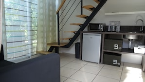Een functionele keuken met een koelkast, magnetron, spoelbak en opslagkastjes.