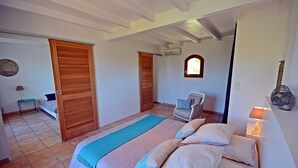 Een slaapkamer met een bed, een raam, een stoel en een lamp.