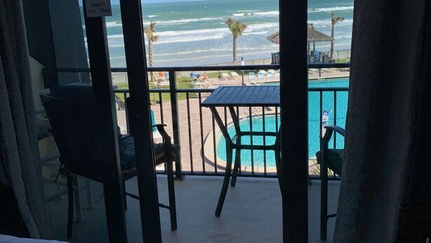 Un balcón con piscina, sillas y vista a la playa y al océano.