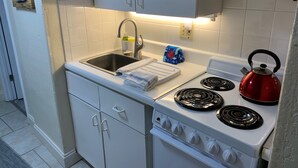 Cocina compacta con fregadero, estufa y microondas.