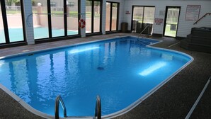 Piscina interior con agua cristalina, un flotador salvavidas y un cartel de prohibido fumar.