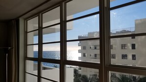 A view through a window with multiple panes, revealing a building with balconies and a clear sky. - Lincoln Rd & Collins Ave,  ROMANTIC 2 PERSON JACUZZI    (Miami Beach)