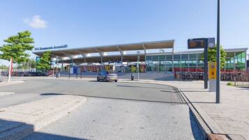 A modern train station with a covered waiting area, a digital information board, and a bicycle parking area.