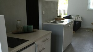 A modern kitchen with a built-in stove, a sink, and a small dining area with a bench.